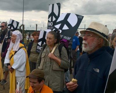 [Demonstrators with placards outside the fence]